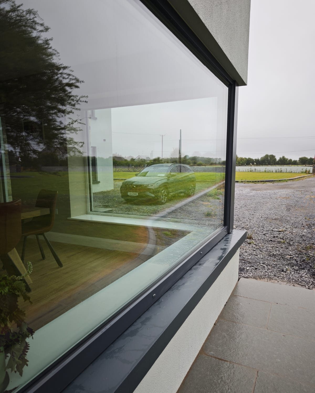 Clean picture window on a new-build home reflecting the garden